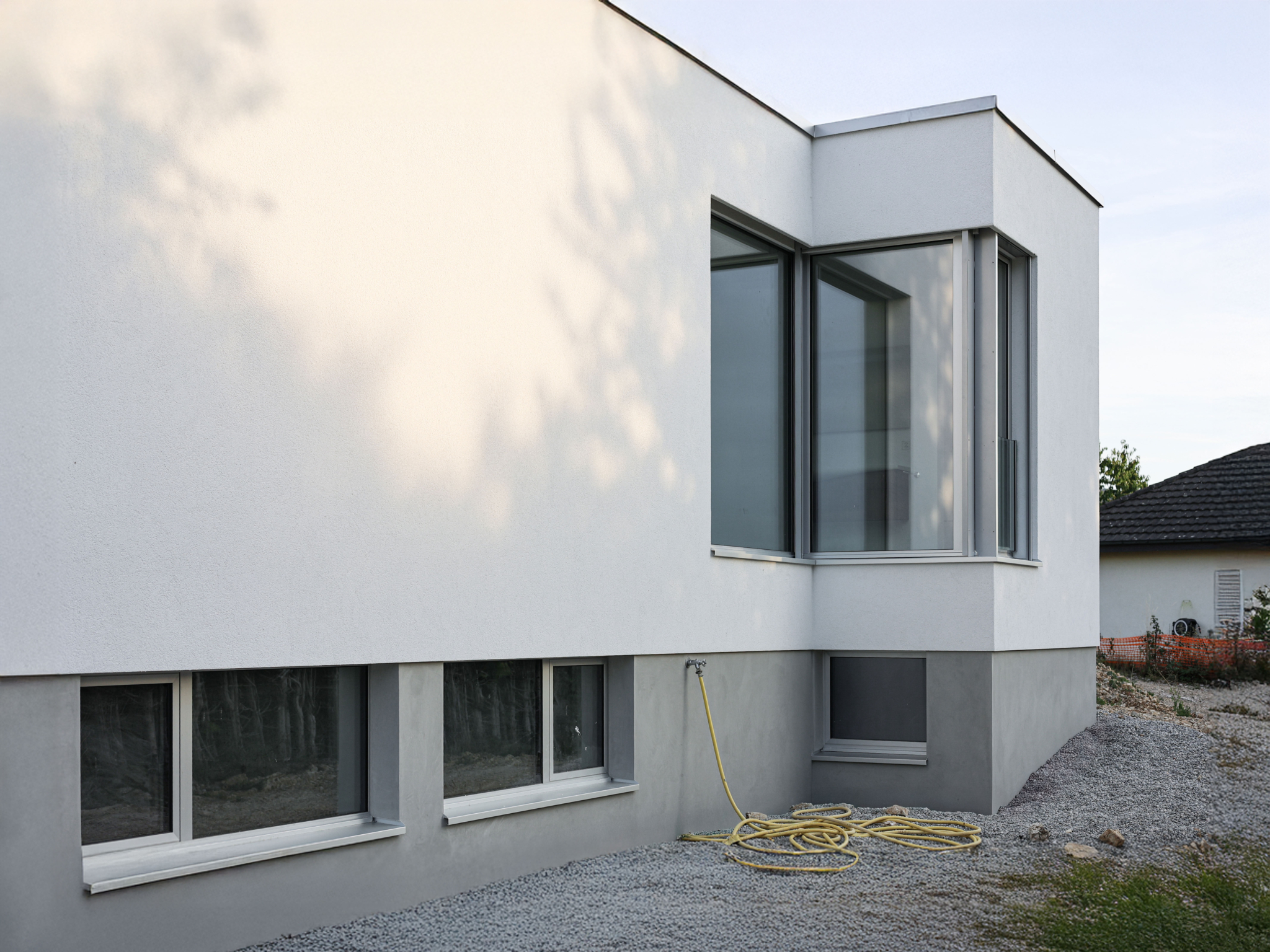 Façade contemporaine d'une villa individuelle Minergie-P à Cornol, caractérisée par des volumes épurés, de larges ouvertures et une architecture ouverte sur le paysage rural